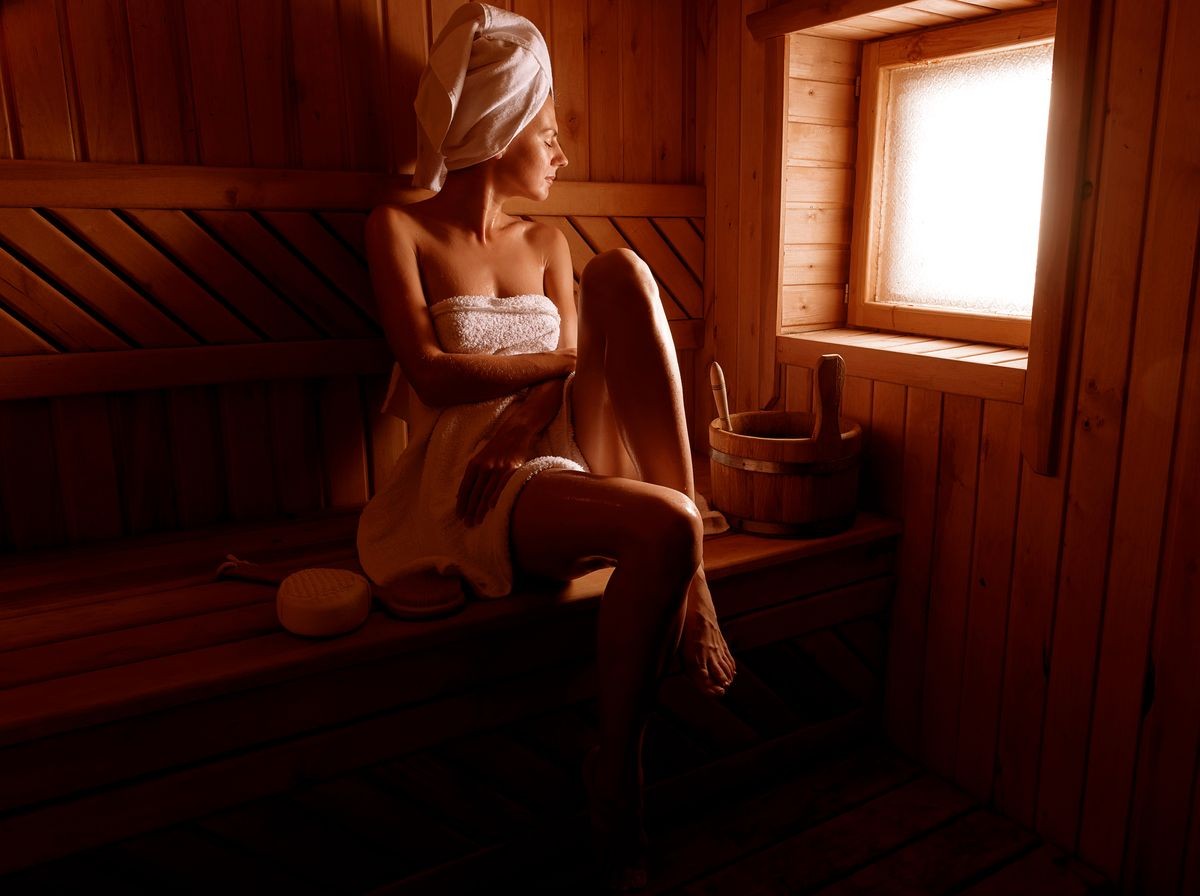 girl in a spa treatment in a traditional sauna with a brush for skin and a washcloth. relaxes wrapped in a white towel