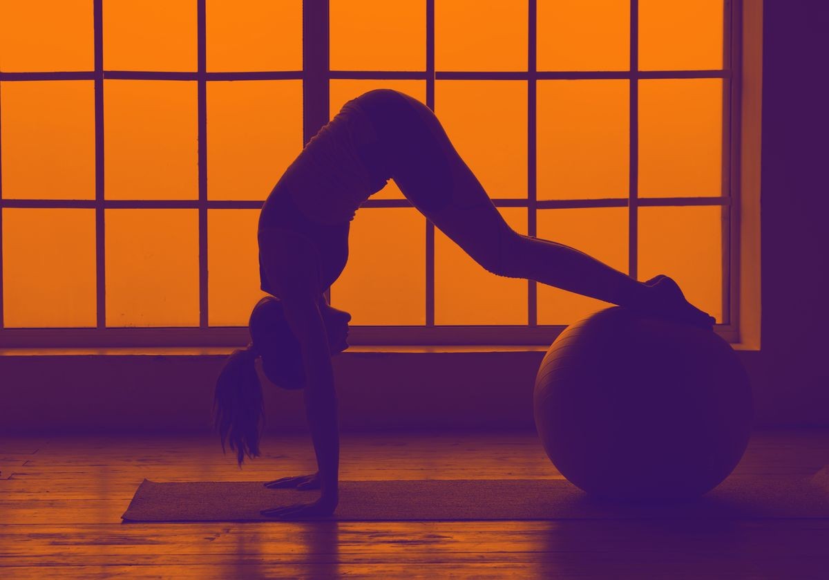 Silhouette of sport woman. Woman doing the fitness ball exercises. Fitness ball.
orange violet toning image.